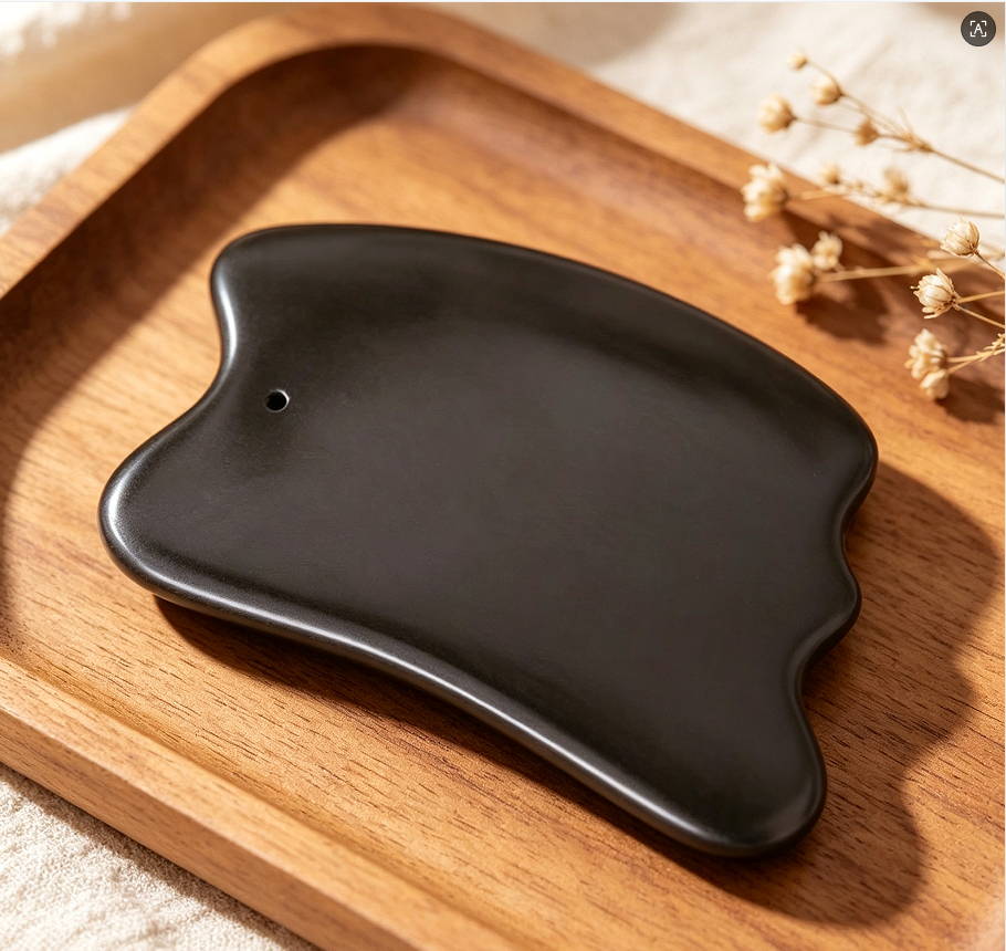 Gua sha tool shown on a wooden tray